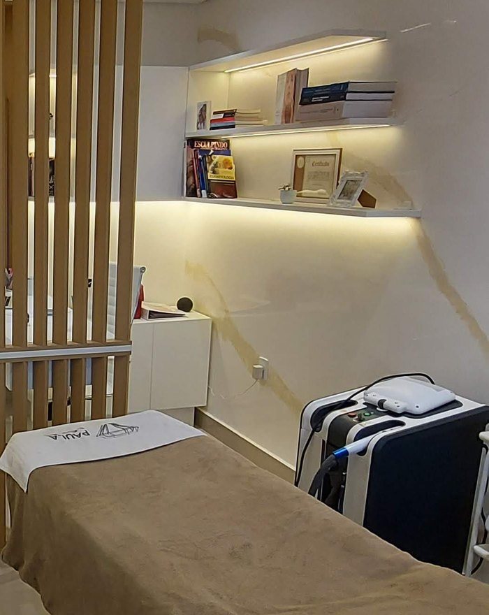 Detalhe de uma sala de atendimento da Lapidare: prateleiras iluminadas, mármore e maca preparada.